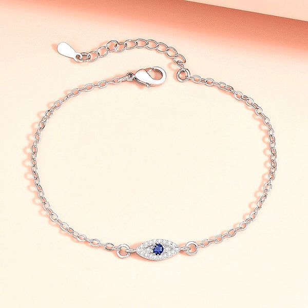 Golden Evil Eye Hand Chain Bracelet with Blue CZ Charm - front view on cream background