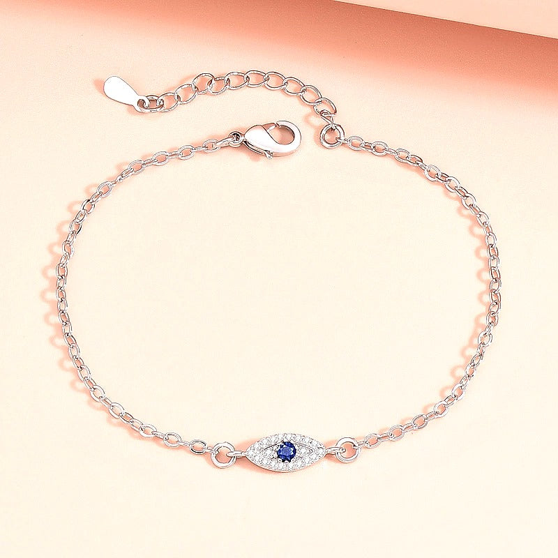 Golden Evil Eye Hand Chain Bracelet with Blue CZ Charm - front view on cream background